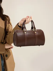 Elegant retro brown Boston pillow bag for women, stylish leather handbag held by model