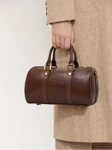 Vintage brown leather Boston pillow bag for women with gold hardware held by hand.