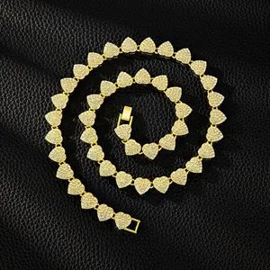 Detailed macro view of an iced-out heart necklace with gold plating and clear stones.