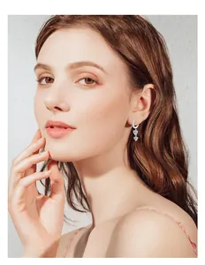 Detail view of a model wearing sparkling heart moissanite tassel earrings in silver