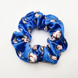 Close-up detail of a blue satin hair scrunchie with a white baseball pattern print
