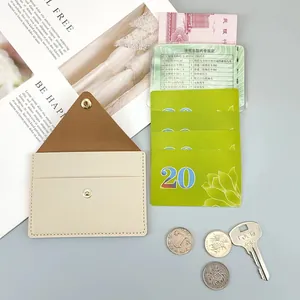 Detail shot of the interior of a slim cream-colored card holder with brown lining