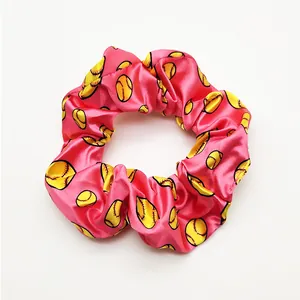 Close-up of pink satin scrunchie with yellow softball pattern print