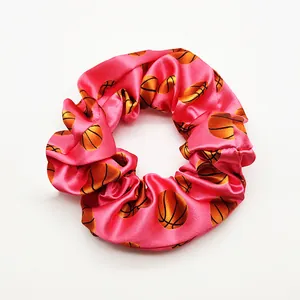Close-up of a pink satin scrunchie with orange basketball prints