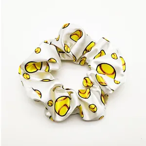 Detailed view of white satin scrunchie with vibrant yellow baseball pattern print