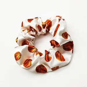 Detailed view of a white satin hair scrunchie with vibrant orange basketball patterns