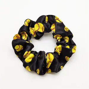 Close-up detail of a black satin scrunchie with yellow softball prints