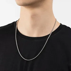 Detailed close-up of a polished silver titanium steel box chain necklace on a male model.