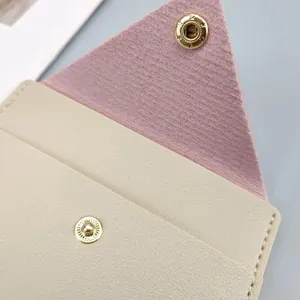 Close-up of slim card wallet showing gold snap button and textured faux leather finish.