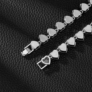 Close-up of silver heart bracelet clasp and textured back of links on black leather