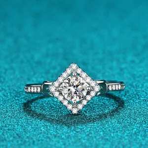 Makroansicht eines 1ct Moissanit-Rings mit Diamant-Halo auf einem blauen Glitzerhintergrund