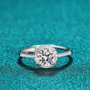 Nahaufnahme eines 1-Karat-Moissanit-Halo-Rings aus Sterlingsilber vor blauem Glitzerhintergrund