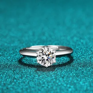 Nahaufnahme eines klassischen Sechs-Krallen-Moissanit-Rings auf blauem Glitzergrund.