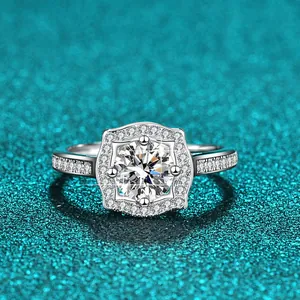 Nahaufnahme eines 1-Karat-Moissanit-Rings mit Halo-Fassung auf funkelndem blauem Grund.