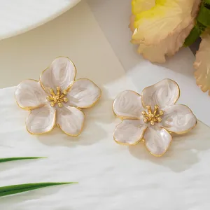 Vue détaillée d'élégantes boucles d'oreilles fleurs en émail blanc nacré et doré