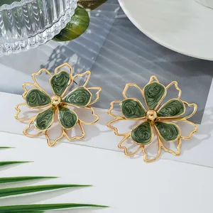 Gros plan détaillé de grandes boucles d'oreilles fleur dorées avec pétales en émail vert