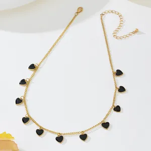 Détail d'un collier chaîne dorée orné de plusieurs petits pendentifs en forme de cœur