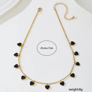 Vue détaillée d'un élégant collier chaîne dorée avec pendentifs cœur noir, 41+7cm