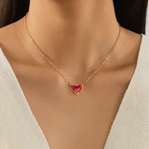 Gros plan d'un pendentif cœur en émail rouge sur une fine chaîne dorée