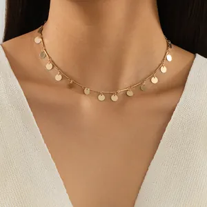 Gros plan du collier minimaliste doré orné de petits pendentifs en forme de pièce