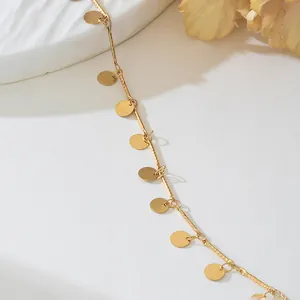 Gros plan d'un collier en métal doré minimaliste avec de petits pendentifs en disque rond