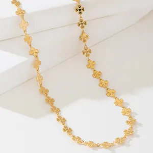 Détail d'un collier en chaîne dorée avec plusieurs breloques en forme de trèfle.