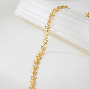 Détail d'un collier à maillons papillon dorés au design ajouré et minimaliste