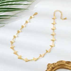 Vue détaillée d'un collier ras du cou papillon doré avec plusieurs charms sur fond blanc
