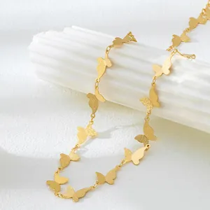 Détail d'un élégant collier à chaîne papillon en or mat sur une colonne cannelée blanche