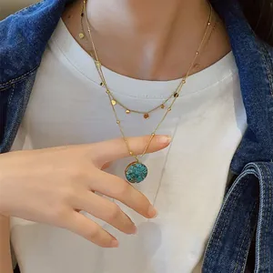Detail shot of a layered vintage turquoise pendant necklace on a female model.