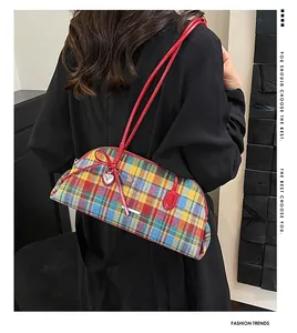 Detail of a vintage plaid shoulder bag with red strap and decorative heart charm.