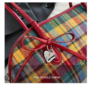 Detailed view of the red bow and silver heart charm on a vintage plaid Boston bag