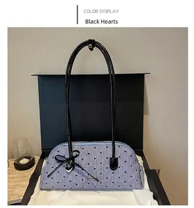 Close-up detail of striped handbag featuring heart pattern and black ribbon bow