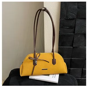 Detail of a yellow vintage Boston shoulder bag with a bow and long brown straps.