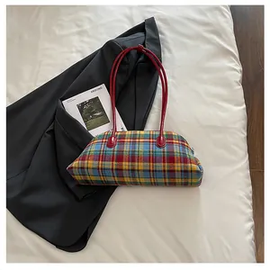 Detail shot of a colorful plaid shoulder bag on a black blazer and white bedding background.