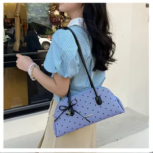 Stylish light blue shoulder bag with heart patterns, black bow, and silver charm