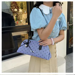 Detail of purple striped shoulder bag with heart pattern and black bow accent