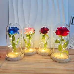 Four artificial roses in glass domes with warm LED lights on a wooden base
