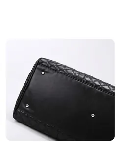 Close-up of protective metal rivets on the bottom of this black quilted leather travel bag