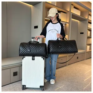Black quilted travel duffel bag with luggage sleeve shown with a white suitcase.