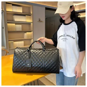 Detailed shot of a black quilted duffel bag held by a model in an elegant interior setting