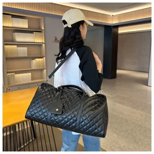 Lifestyle view of large black quilted travel duffle bag with shoulder strap and handles