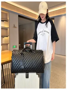Large black quilted travel bag with luggage sleeve shown in a lifestyle airport setting