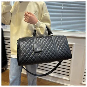 Large black quilted travel bag carried by a model in a stylish and modern indoor setting.