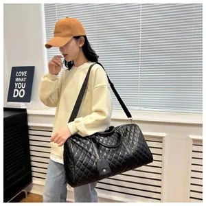 Model showcasing a large black quilted travel duffel bag in a stylish indoor lifestyle setting