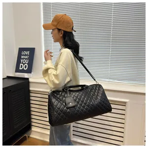 Stylish Asian model carrying a large black quilted travel bag with shoulder strap