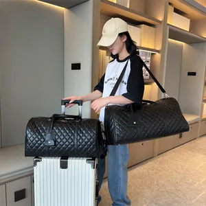 Black quilted duffle bags for travel with luggage sleeve shown with model