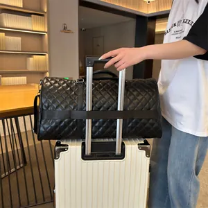 Premium black quilted travel duffle bag with trolley sleeve placed on white suitcase