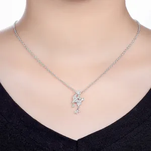 Detail view of a dainty silver star and moon pendant necklace worn on a female neck.