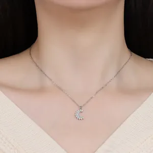 Macro view of model wearing a silver crescent moon pendant necklace with zircons